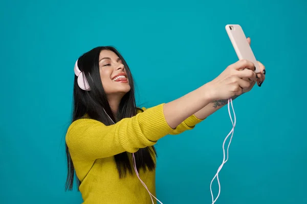 Modelo tomando selfie, mostrando lengua, escuchando música . — Foto de Stock