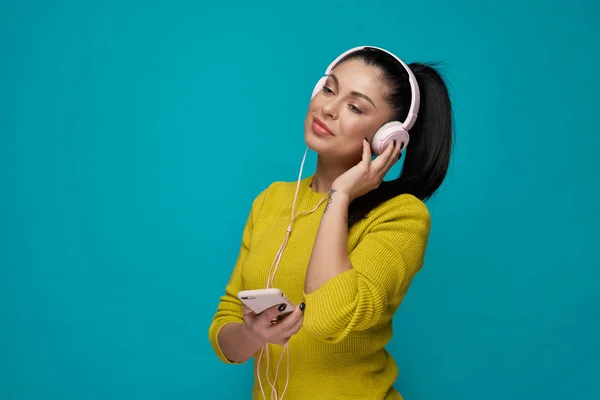 Model with pony tail listening music in headphones.