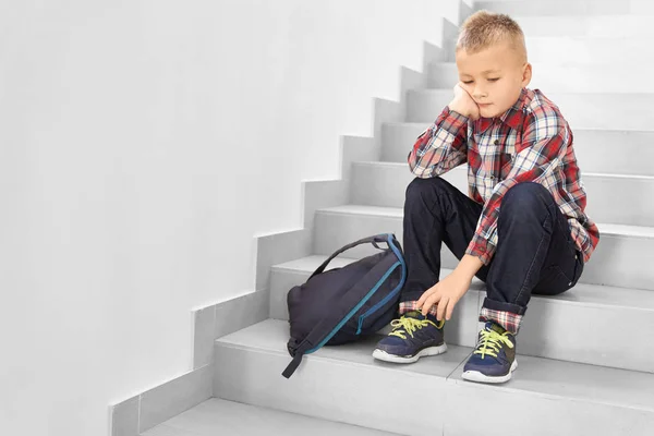 Traurig blonde Schuljungen, die allein auf der Treppe sitzen. — Stockfoto