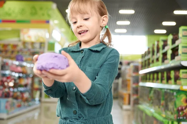 Девушка держит в руках фиолетовый кинетический песок, позирует перед камерой . — стоковое фото