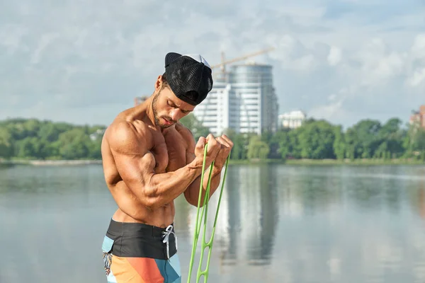 Homme musculaire faisant des exercices de puissance avec un expanseur en caoutchouc . Images De Stock Libres De Droits