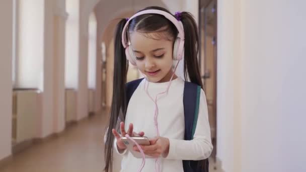 Front view of little schoolchild keeping phone in school — Stock Video