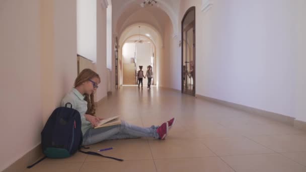 Menina sentada no chão, lendo livro e se preparando para a lição — Vídeo de Stock