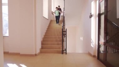 Çocuklar aşağı iniyor ve okulda koridorda koşuyorlar.