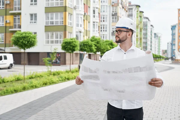 Homme avec projet architectural sur papier regardant la maison . Photos De Stock Libres De Droits