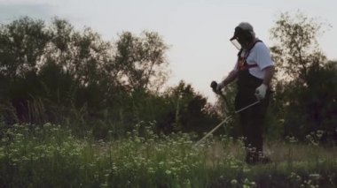 Bahçede çalışan koruyucu maske ve tulum giyen adam