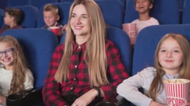 Film izleyen çocuk grubu ile genç kreş öğretmeni