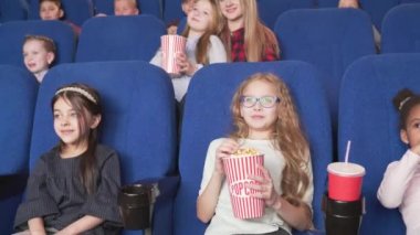 Sevimli kız sinemada başka mutlu çocuklar ile karikatür izlerken