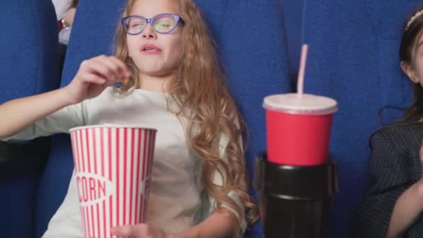 Счастливые многорасовые дети едят попкорн и смотрят кино — стоковое видео