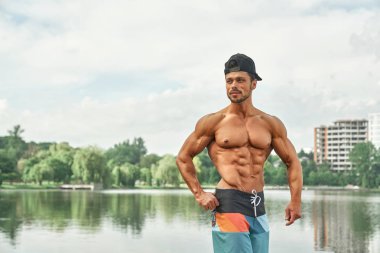 Kaslarını gösteren kaslı çıplak gövdeli adam.