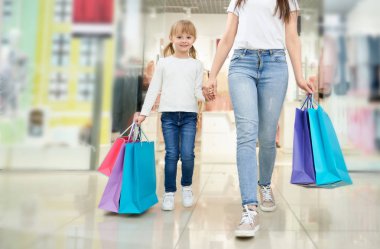 Mağazada renkli alışveriş poşetleri ile çocuk ve anne.