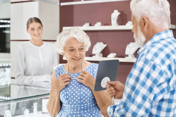 Lycklig åldrad kvinna väljer lyx pärlhalsband på Store — Stockfoto