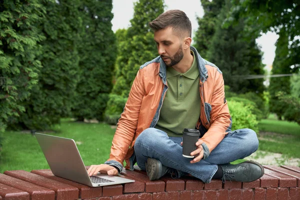 Estudante trabalhando em laptop com xícara de café no jardim . — Fotografia de Stock