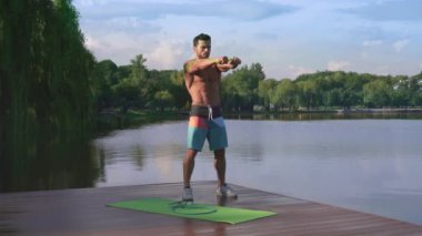 Yakışıklı adam kauçuk genişletici tarafından kollar için egzersizler yapıyor