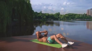 Tahta göl rıhtımında karın kası egzersizi yapan güçlü bir adam.