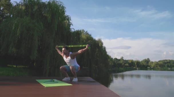 Jeune bodybuilder en vêtements de sport faire squat dehors — Video