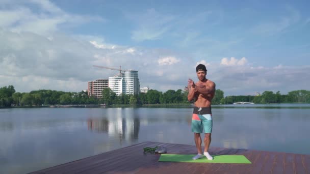 Bodybuilder δείχνει το μυϊκό σώμα του στην κάμερα κοντά στη λίμνη — Αρχείο Βίντεο