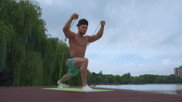 湖の近くで腕のための練習をしている強力な男性アスリート — ストック動画