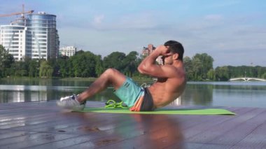 Yakışıklı fitness modeli yoga minderinde abdominal mekik çekiyor.