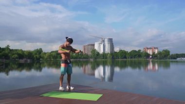 Genişletici kullanarak kol germe kaslı adam ile Göl iskelesi