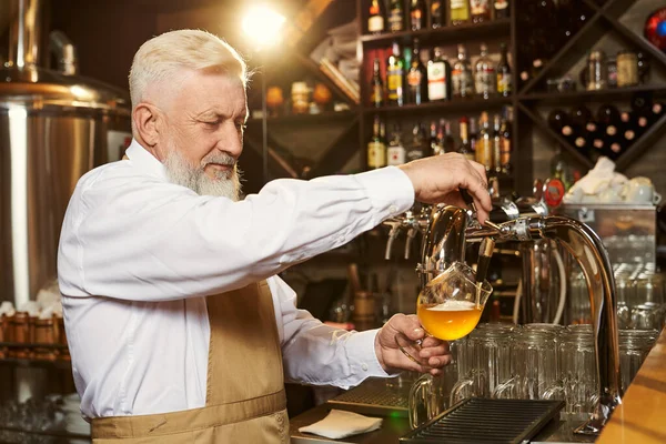 Barman nalewanie lekkiego piwa w szklance z kranu piwa. — Zdjęcie stockowe