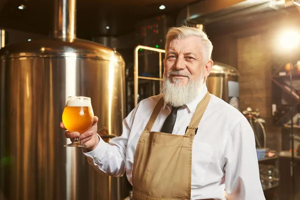 Cervecero sosteniendo vidrio de cerveza fría con espuma . —  Fotos de Stock