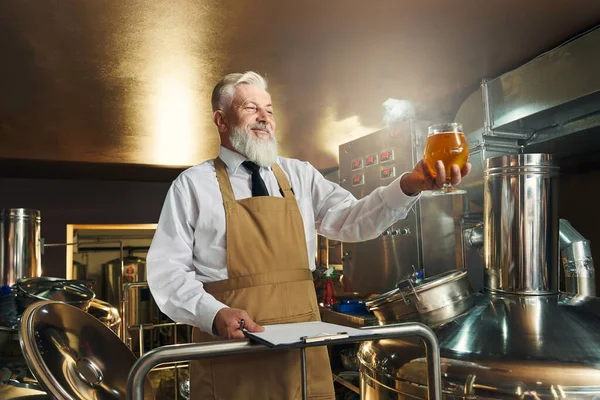 Specjalista browar szuka gospodarstwa szklankę piwa. — Zdjęcie stockowe