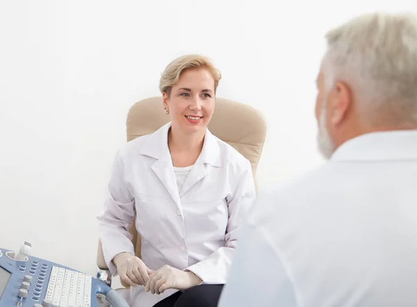 Dottore sorridente e guardando il paziente durante la consultazione . — Foto Stock