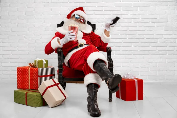 Wesoły Święty Mikołaj siedzi w fotelu i ogląda telewizję — Zdjęcie stockowe