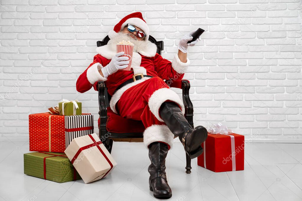 Cheerful Santa Claus sitting in armchair and watching TV