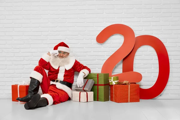 Przemyślany Święty Mikołaj siedzi na podłodze z pudełkami prezentów — Zdjęcie stockowe