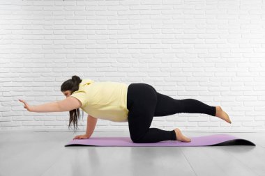 Genç tombul kadın içeride menekşe paspasın üzerinde geriniyor.