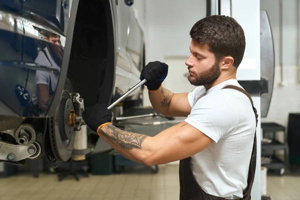 Blick von der Seite eines gutaussehenden Mannes, der Autoreifen wechselt — Stockfoto