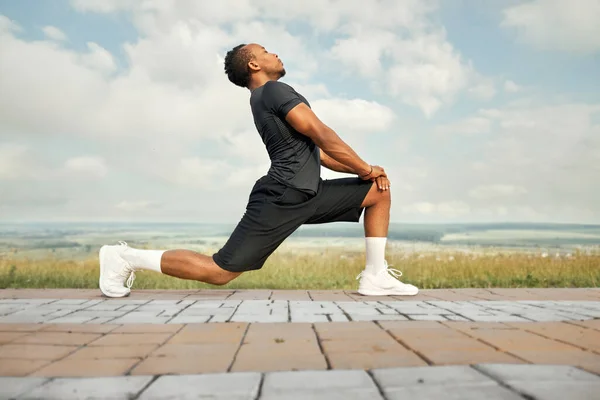 Αθλητικός τύπος κάνει τεντώνοντας ασκήσεις σε εξωτερικούς χώρους. — Φωτογραφία Αρχείου