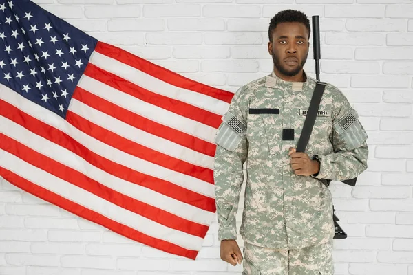 Soldado americano vistiendo uniforme cerca de bandera nacional . — Foto de Stock