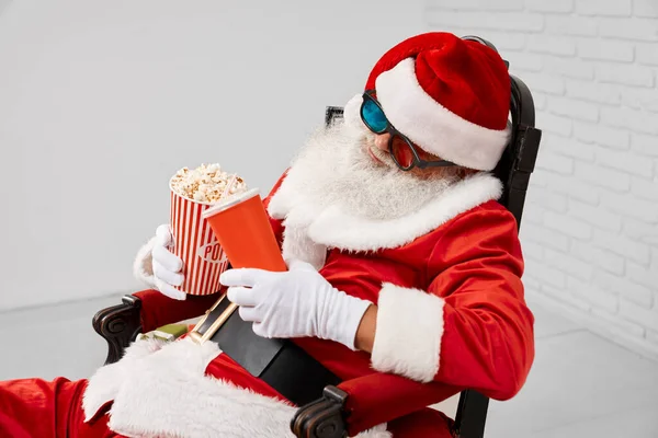 Śpiący Święty Mikołaj w fotelu z popcornem i colą — Zdjęcie stockowe