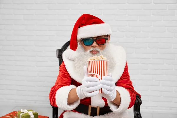 Mikulás karosszékben nézi csíkos vödör popcorn — Stock Fotó