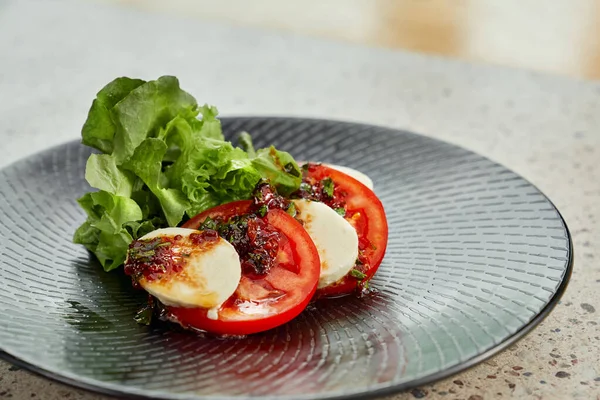 Ensalada Caprese en plato negro . — Foto de Stock