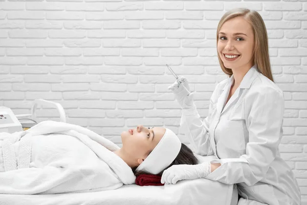 Cosmetologo posa, tenuta siringa durante la procedura . — Foto Stock