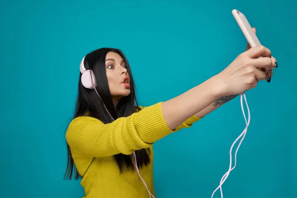 Mujer joven divertida usando auriculares y tomando selfie — Foto de Stock