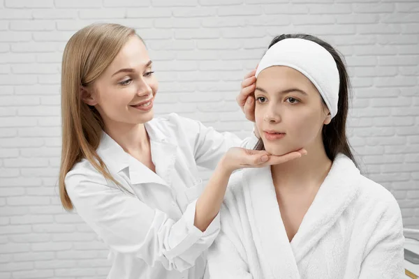 Esteticista examinando la cara del cliente en el gabinete de cosmetología . — Foto de Stock