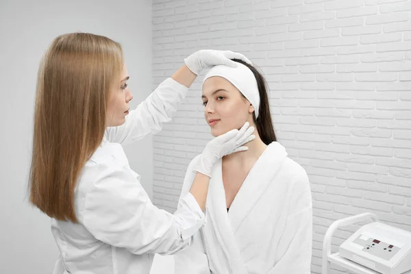 Médico cosmetólogo inspeccionando la cara del paciente . — Foto de Stock