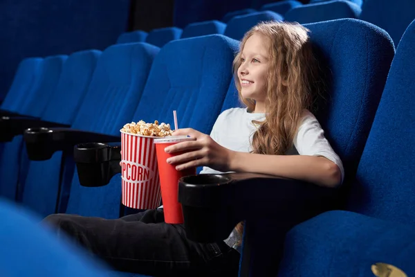女の子は一人で映画館に座ってコミカルな映画を見て — ストック写真