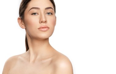 Makyajsız esmer beyaz arka planda kameraya bakıyor.