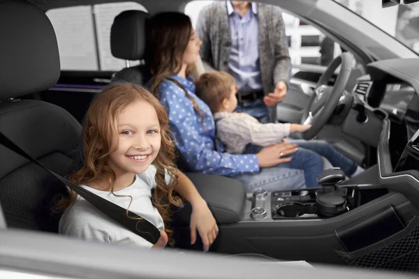Söt flicka sitter i ny stor bil i auto showroom — Stockfoto