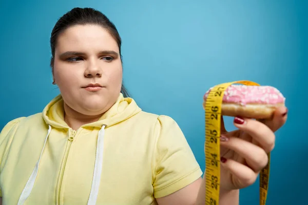 Porträt eines dicken Mädchens mit Donut und Maßband — Stockfoto