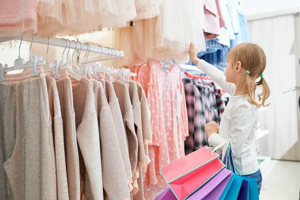 Mağazada duran ve yeni elbiseler seçen küçük müşteri — Stok fotoğraf