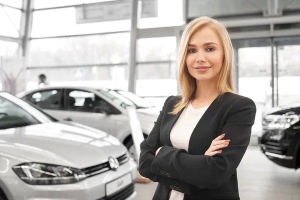 Negociante de carro feminino com braços dobrados em pé no salão de auto — Fotografia de Stock