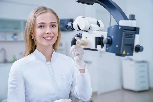 Adorable dentista femenina posando y sonriendo en la clínica . — Foto de Stock