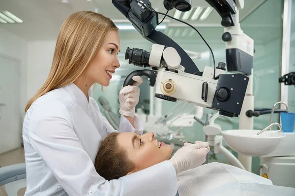 Dentista che esamina i denti utilizzando il moderno microscopio dentale . — Foto Stock